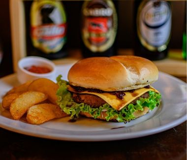 Hamburguesa tradicional con carne, tocino, queso, tomate y lechuga en pan brioche, servida en Carpe Diem Restaurante, zona 1.