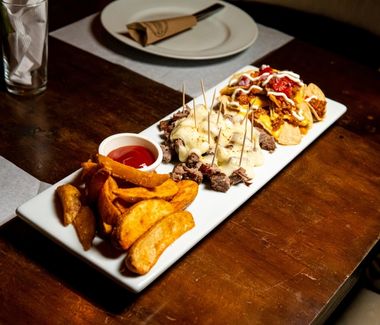 Tablazo de Asado con lomito o puyazo importado, bañado en queso mozzarella, con papas en gajo y nachos, servido en Carpe Diem Restaurante, zona 1.